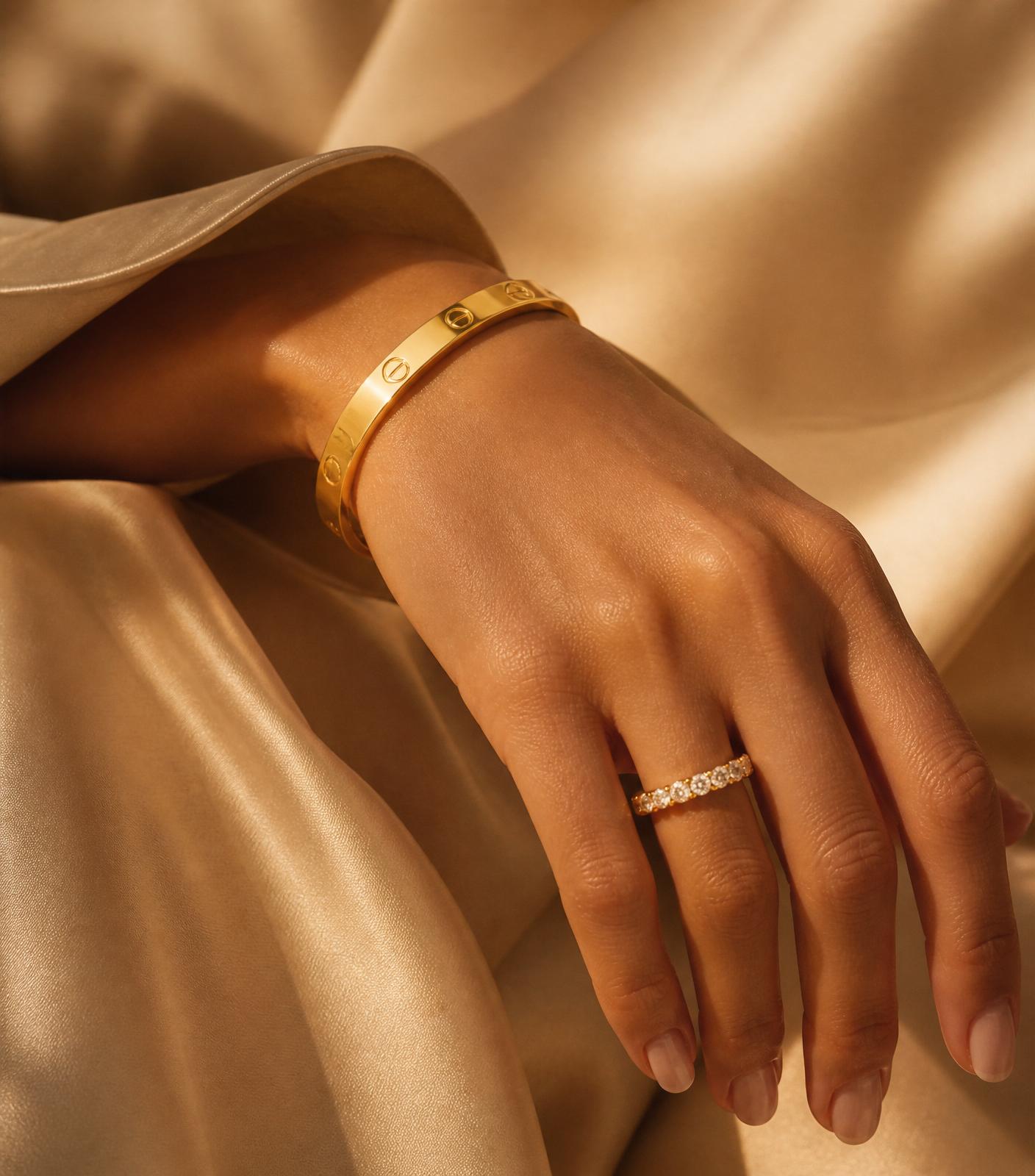 Gold bangle resting on champagne silk in warm sunlight